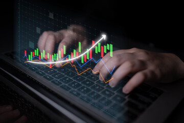 Close-up view of hands typing on a laptop keyboard with a dynamic financial graph overlay demonstrating stock market trends and data analysis in a professional setting. Impute