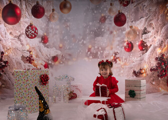 Kleines lachendes M&auml;dchen mit rotem Kleid freut sich &uuml;ber die Weihnachtsgeschenke. 