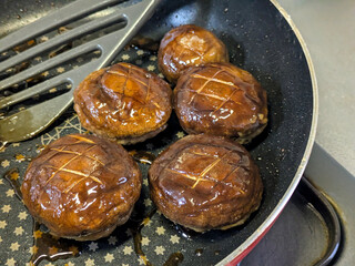 フライパンで焼かれたしいたけの肉詰め料理 美味しい照り焼き味