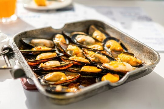 Freshly cooked mussels in sauce served in metal pan