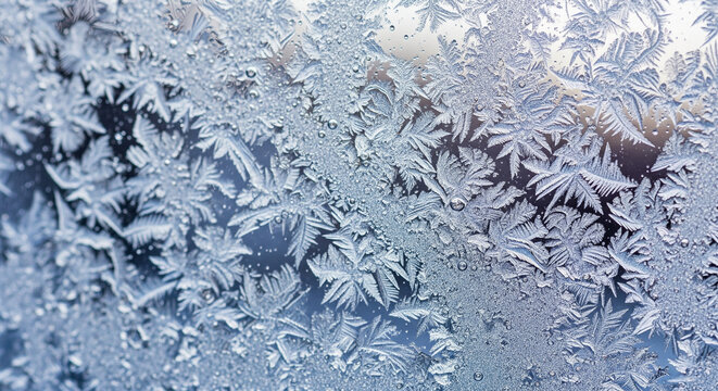 Close-up frost patterns on glass, resembling delicate ice crystals and snowflakes, showcasing winter's artistry