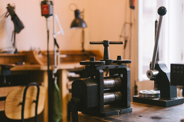 printing press workshop with vintage rollers and equipment on wooden bench, industrial tools and hand operated machinery for craft printing and rolling in creative studio space