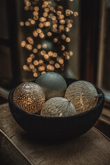 Elegant glowing christmas ornaments in a dark bowl with warm festive bokeh lights in the background