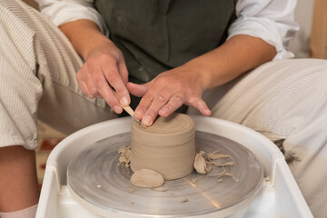 Hands creating pottery on potter's wheel with clay