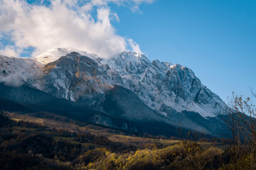 Snow-capped Gran Sasso d'Italia mountains glowing under sunlight with autumn colored valley below
