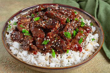 crispy beef, with green onions and sesame seeds, on a rice pad, in a bowl with chopsticks, on a textured surface, no people