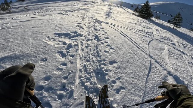 First person view of ski touring or splitboarding uphill in bright winter sun