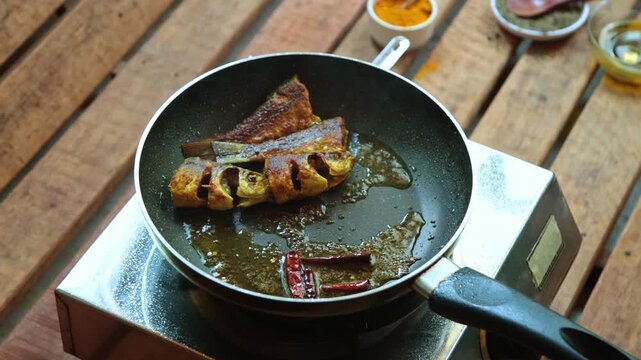 Fish pieces are frying in pan in mustard oil.