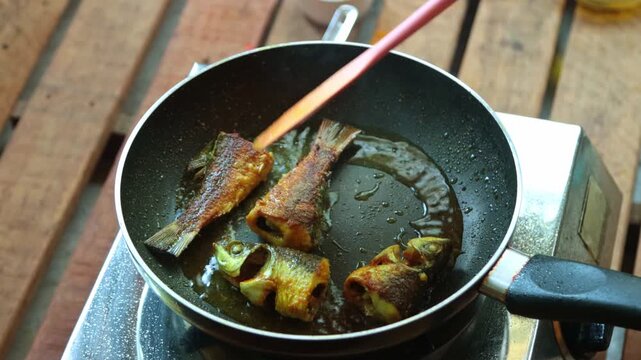 Fish pieces are frying in pan in mustard oil.