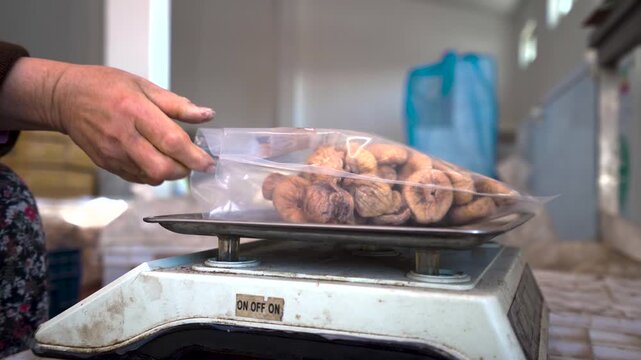 Woman worker packing and weighing dried figs