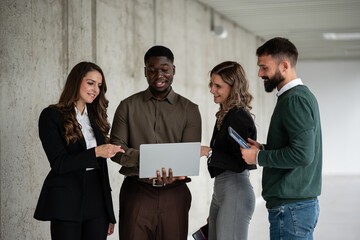 Diverse business people collaborating on laptop in office hallway