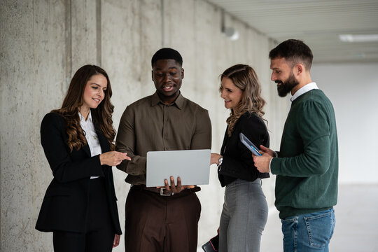 Diverse business people collaborating on laptop in office hallway