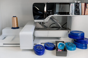 Modern sewing machine and blue containers with sewing pins.