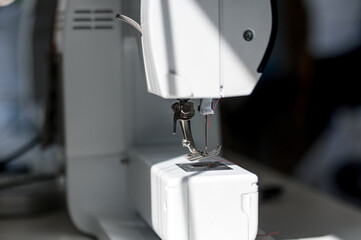 Close-up of the presser foot and needle of a modern white sewing machine