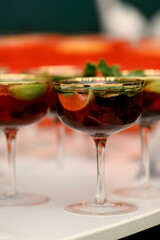 A row of lime and mint cocktails in gold-rimmed glasses on a white bar table.