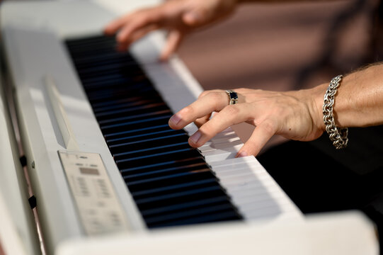 Close-up of male hands playing the keys of a white digital piano synthesizer. - Powered by Adobe