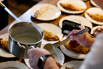 A chef spoons cream onto desserts on plates during a banquet.