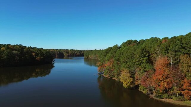 Aerial flyover shot of Lake Johnson park in Raleigh North Carolina with beautiful fall foliage