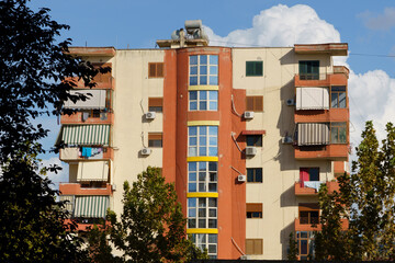 Fototapeta premium A renovated stucco home with older air conditioners stands on a lively city street. Perfect for rental listings, real estate agencies, foreign buyers, and modernizing urban neighborhoods.