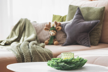 Cozy Living Room with Crocheted Reindeer Toy on Sofa and Christmas Holiday Candle Decor on Table