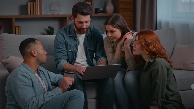 Multiethnic team four friends colleagues looking laptop on sofa diverse multiracial creative ethnic group people men women gathered at home party in casual office talking discussing online project