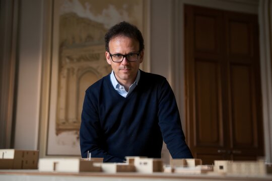 Architect Poses with Architectural Models in Historic Room