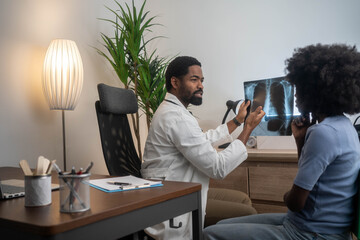 Black doctor reviewing chest X-ray with African American female patient in clinic