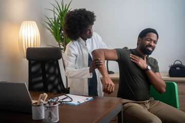 Therapist treating a male injured by rotator cuff stretching method.