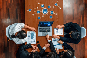 Aerial view of a diverse business team engaged in a dynamic meeting, reviewing data analysis on a laptop while discussing strategies and insights for success. Amity