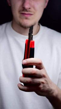 A man in a white T-shirt holds a retractable utility knife.
Retractable knife blade.
Knife, cutter, dangerous, blade, steel, equipment
