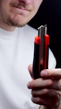 A man in a white T-shirt holds a retractable utility knife.
Retractable knife blade.
Knife, cutter, dangerous, blade, steel, equipment