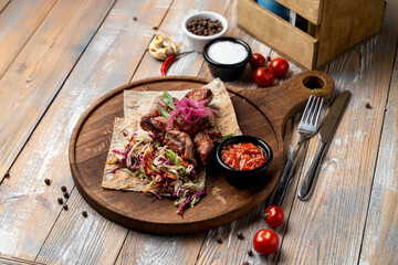 Tender grilled meat is artfully arranged on a wooden board, surrounded by colorful salad and flavorful sauces. The rustic table adds warmth to this enticing meal