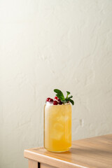 A vibrant mocktail filled with citrus flavors, berries, and fresh mint rests on a wooden table. Sunlight creates a warm atmosphere, ideal for summer celebrations and gatherings