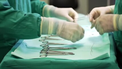 Surgeons preparing for operation with sterile instruments on a green surgical drape in an operating room. - Powered by Adobe