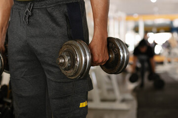 Person holding a dumbbell at the gym, focusing on strength training and physical fitness development