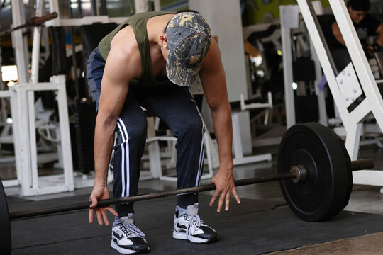 Man preparing to perform a deadlift with a barbell, engaging in strength training workout at the gym