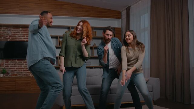 Happy multiracial four diverse people friends dancing energetic at home party smiling relaxing ethnic millennials free men women laughing dance funny having fun listening music moving in living room