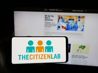 Fototapeta premium Stuttgart, Germany - 11-19-2025: Person holding smartphone with logo of Canadian research laboratory Citizen Lab on screen in front of website. Focus on phone display.
