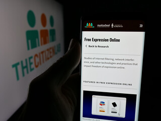 Fototapeta premium Stuttgart, Germany - 11-19-2025: Person holding cellphone with webpage of Canadian research laboratory Citizen Lab on screen in front of logo. Focus on center of phone display.