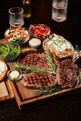 Grilled steak assortment served with fresh sides and herbs
Beef steaks on wooden boards with vegetables and sauces
Steak platter featuring ribeye and rustic garnishes