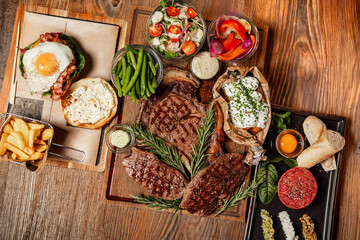 Grilled steak assortment served with fresh sides and herbs
Beef steaks on wooden boards with vegetables and sauces
Steak platter featuring ribeye and rustic garnishes