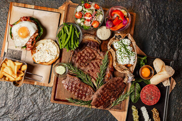 Grilled steak assortment served with fresh sides and herbs
Beef steaks on wooden boards with vegetables and sauces
Steak platter featuring ribeye and rustic garnishes