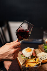 Hand holding a glass of red wine at an elegant dinner
Red wine served in a stylish glass with food in the background
Close-up of red wine in a glass during a dining moment