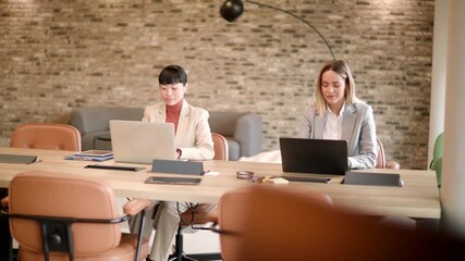 Two professionals engage in an inspiring brainstorming session, sharing ideas and working on their laptops in a modern, well lit workspace.
