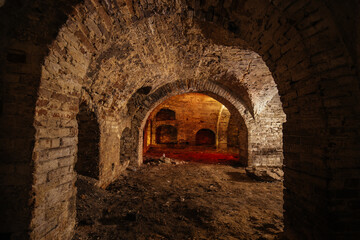 Dark and creepy vaulted red brick cellar under old castle
