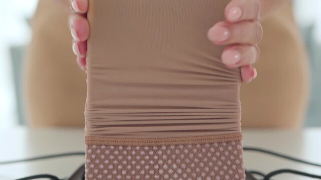 Careful hands stretch a medical compression stocking onto the loading frame for easier home application