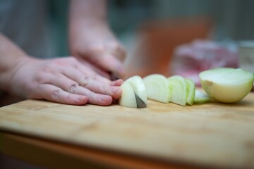 Girl cutting onion into half-rings on bamboo board with vintage metal knife