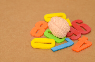 Cognitive Data Processing: Human Brain Resting on a Vibrant Pile of Oversized Foam Numbers, Symbolizing Analytical Thinking and Complex Calculation.