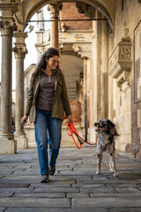Woman and dog enjoying a walk together along an old city portico