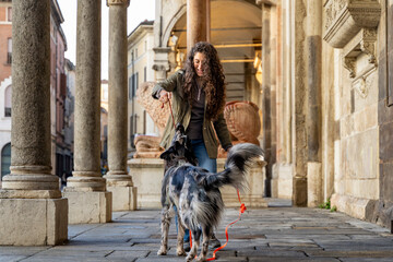 Woman playing with happy dog on leash in an historic city arcade